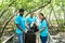 Three volunteers in work overalls collect garbage in forest in plastic bag. Close-up during action. Cleaning of nature from waste