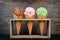 Three waffle cones of ice cream in rustic holder over slate