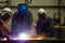 Three welders in masks working with metal Welding process.