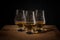 Three whisky glasses on a wooden table