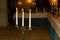 Three white candles in the elegant candle holder decorating a table served for a celebration dinner