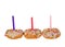 Three white frosted sprinkle donuts with candles isolated