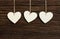 Three White Love Valentine\'s hearts hanging on wooden texture ba