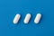 Three white oblong tablets lie on a blue background.