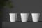 Three white paper cups standing on gray table