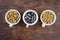 Three white single serving bowls with blackberry crumble dessert, on a wood background