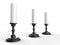 Three white wax candles on black shiny candle holders