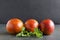 Three whole blood oranges and fresh mint on the dark rustic surface against black background