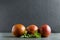 Three whole blood oranges and fresh mint on the dark rustic surface against black background