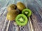 Three whole kiwi fruit and two half.  Tropical green fruit on a wooden table. Close up