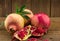 Three whole pomegranates, seeds and pieces isolated on rustic wo