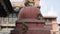 Three wild nepalese monkeys are sitting at the foot of an ancient stupa. Red bricks building. Kathmandu Nepal.