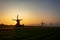 Three wind mills in the morning mist and a rising sun