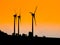 Three wind turbines used for ecological producing electric energy. Sunset silhouettes