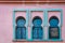 Three windows with emerald green arch in pink wall. Morocco