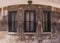 Three windows with ornamented metal lattice on a stone building