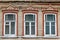 Three windows in a row on a wall of an old russian house decorated with wood carving