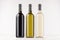 Three wine bottles different colors - transparent, green, black- on white wooden board, mock up.