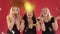 Three women in black dresses blowing confetti in studio