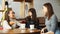 Three women girlfriends in a cafe are talking and drinking their beverages.