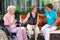 Three women sitting chatting on a garden bench.