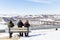 Three women sitting on park bench in winter time.