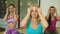 Three women smile and make themselves a facial massage