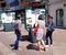 Three women stand in front of a city bulletin board and read information about cultural events and comment it on the town square