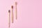 Three wooden bamboo toothbrushes on a pink background, top view.  Dental care concept