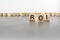 three wooden blocks with letters ROI with focus to the single cube in the foreground in a conceptual image on grey