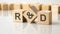 three wooden cubes with the letters R and D on the bright surface of a gray table, business concept