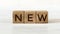 Three wooden cubes with word NEW, on white table