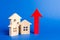 three wooden houses and red up arrow. Real estate value increase. High rates of construction, high liquidity. Supply and demand