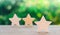 Three wooden stars on a green bokeh background. The concept of the rating of hotels and restaurants, the evaluation of critics and