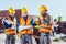 Three workers in hardhats examining building plans and talking on portable radio