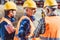 Three workers in hardhats and reflective vests standing at construction site and talking