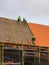 Three workers in protective workwear installing new clay tiles roof, new clay tiles layer covering