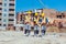 Three workers in reflective vests and hardhats walking together across construction site and discussing building