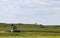 Three working pump jacks on oil or gas wells out in a green field