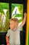 A three-year-old little fair-haired boy rides in a yellow-green children`s train in an amusement park in Riviera, Sochi, facing