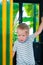 A three-year-old little fair-haired boy rides in a yellow-green children`s train in an amusement park in Riviera, Sochi, facing