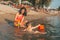 Three year old toddler boy playing with beach toys with mother in the water