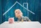 Three years old child sitting st the table with money and a piggybank