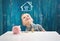 Three years old child sitting st the table with money and a piggybank