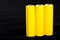 Three yellow batteries close-up on a dark black blurred background. Electrics. Battery power. Accumulator on the fabric with vill