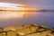 Three yellow metal boats tied together on calm lake at dawn under a brilliant gold and violet sunrise