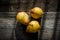 Three yellow pears on a barn wood plank table with shadows from the sun