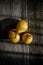 Three yellow pears on a barn wood plank table with shadows from the sun