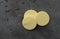 Three yellow round candy wafers on a gray background illuminated with natural light top view