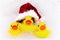 three Yellow rubber ducks for bathing in a red Santa hat lies in the bathroom among relaxing bubble baths, front view